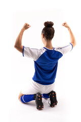 Biracial young female player with arms raised and clenched fist kneeling on white background