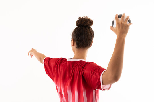 Biracial young female handball player throwing ball while standing against white background