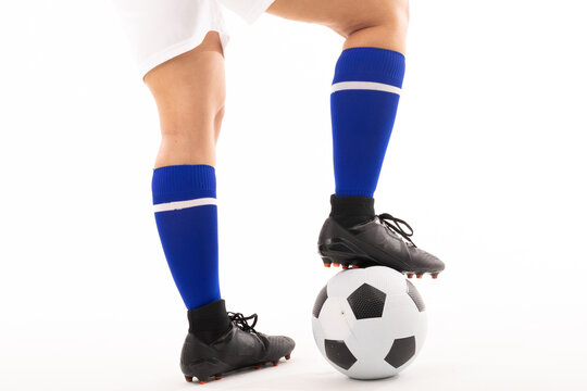 Low section of biracial young female player with foot on soccer ball against white background