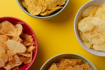 Overhead close-up of various snacks in bowls on yellow background