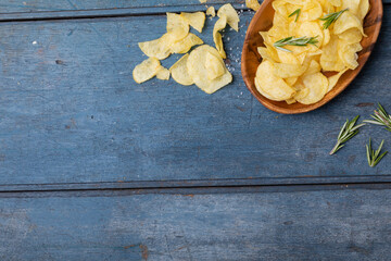 Directly above shot of potato chips with rosemary in bowl and table with empty space