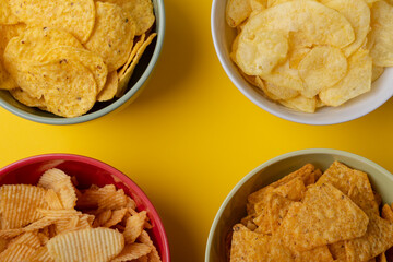 Overhead view of various snacks in bowls on yellow background