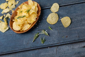 Foto op Canvas High angle view of potato chips in bowl with rosemary and salt on wooden table © WavebreakMediaMicro