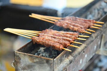 typical skewers of lamb arrosticini cooking on a charcoal grill barbecue close up view selective focus.