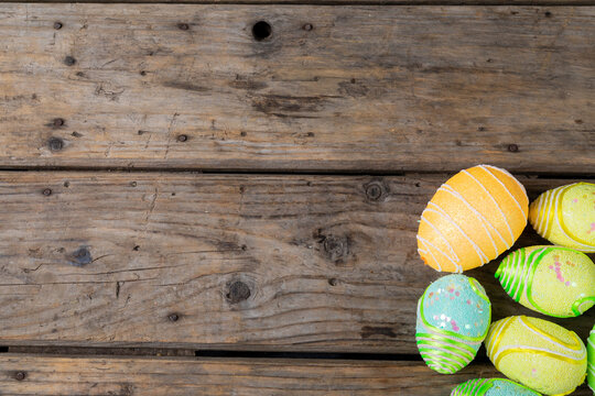 Overhead view of decorated colorful easter eggs on wooden table with empty space