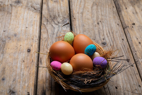 Close-up of easter eggs with colorful candies in nest on wooden table