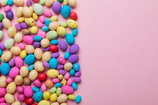 Directly above shot of colorful candy easter eggs arranged on pink background with copy space