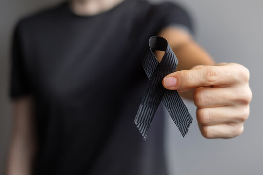 Woman holding black Ribbon for Melanoma and skin cancer, Vaccine injury awareness month, grief and rest in peace. Healthcare and Racist concept