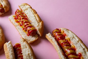  High angle view of yellow and red sauces on hot dogs over pink background © WavebreakMediaMicro