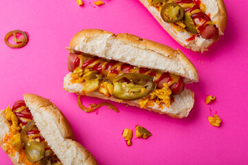 Directly above close-up of hot dogs on pink background