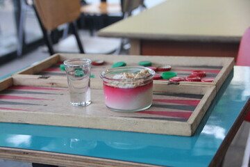 Malabi served with nuts and coconut shavings on a backgammon board 