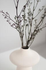 White vase on a white table with twigs.