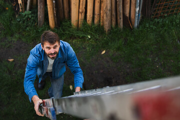 High angle view of mature man climbing up the ladder