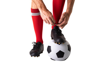 Low section of young male caucasian player tying shoelace on soccer ball over white background