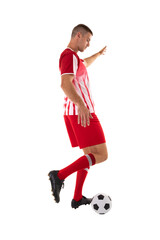Young male caucasian athlete kicking soccer ball against white background