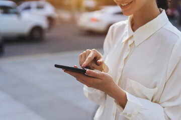 Close up of hands using smart phone with background of the city, girl texting with friends while walking outdoor