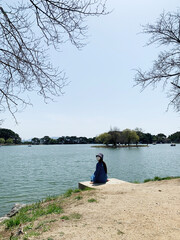 Fototapeta na wymiar 충북 제천 의림지, 제천 10경 중 1경, 저수지를 바라보고 앉아 있는 마스트를 끼고 있는 여자 / Uirimji in Jecheon, Chungcheongbuk-do, 1 out of 10 scenic spots in Jecheon, a woman wearing a mast sitting facing the reservoir 