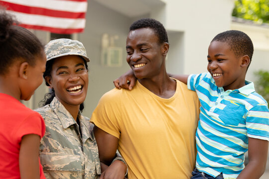 Cheerful female mid adult african american soldier with family outside house
