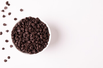 Overhead view of bowl full of chocolate chips by copy space on white background