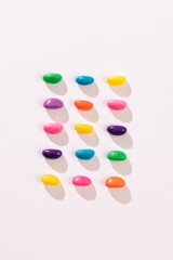Overhead view of multi colored candies arranged in a row by copy space against white background