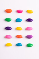 Directly above view of multi colored candies arranged in a row over white background