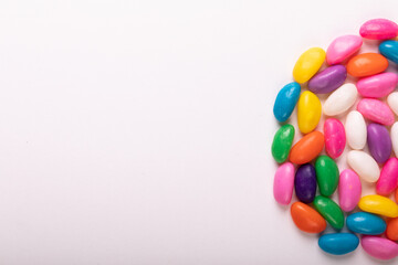 Directly above view of colorful candies arranged in semi-circle by copy space on white background