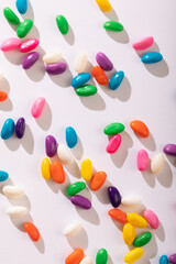 Directly above view of multi colored candies scattered against white background