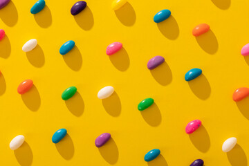Full frame shot of multi colored candies arranged in a row on yellow background