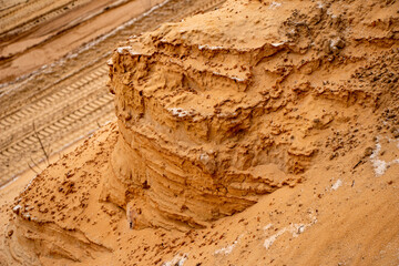 Textural sand, with  relief surface, multi-colored layers and different in size of granules, in outdoor sand career, after mining ore and sand for construction.