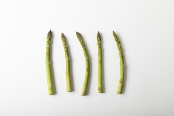 Directly above view of raw asparagus arranged side by side with copy space on white background