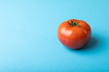 Close-up of fresh red tomato by copy space against blue background