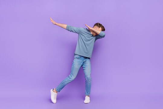 Photo of funny adorable guy wear grey shirt having fun dancing showing dab isolated violet color background