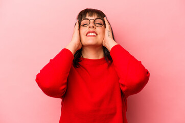 Young caucasian woman isolated on pink background laughs joyfully keeping hands on head. Happiness concept.