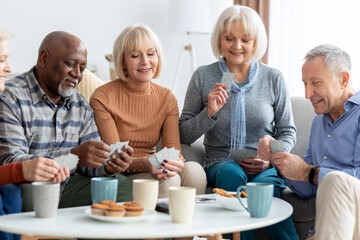Fototapeta na wymiar Happy senior people playing cards at nursing home