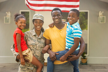 Portrait of happy female mid adult african american soldier with family outside house