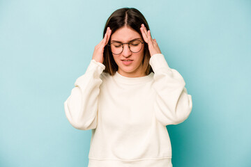 Young caucasian woman isolated on blue background touching temples and having headache.