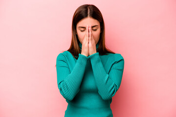 Young caucasian woman isolated on pink background holding hands in pray near mouth, feels confident.