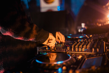 Close up view of a dj's hands playing the mixer while performing in a music festival. High quality photo