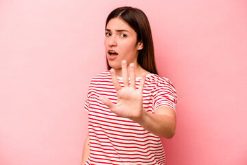 Young caucasian woman isolated on pink background being shocked due to an imminent danger