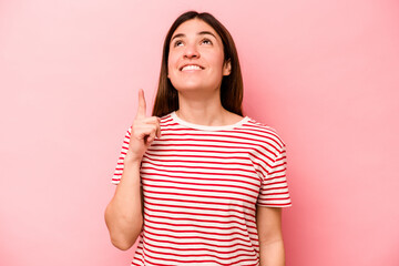Young caucasian woman isolated on pink background indicates with both fore fingers up showing a...