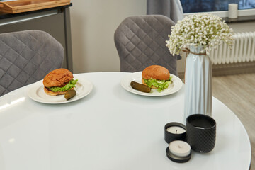 dining table with two burgers on white plates. food to be eaten. lunch, dinner, fast food, delicious food