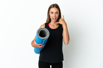 Obraz premium Sport woman going to yoga classes while holding a mat over isolated white background making phone gesture. Call me back sign