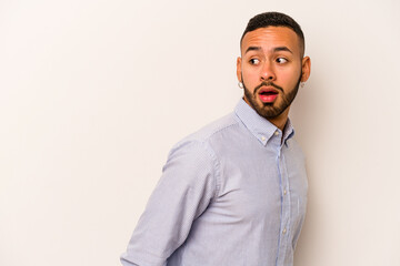 Obraz premium Young hispanic man isolated on white background looks aside smiling, cheerful and pleasant.