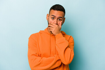 Young hispanic man isolated on blue background scared and afraid.