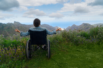 Disabled handicapped woman in wheelchair on mountain hill enjoying view