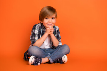 Full body photo of young cheerful boy hands touch chin thoughtful clever isolated over orange color background