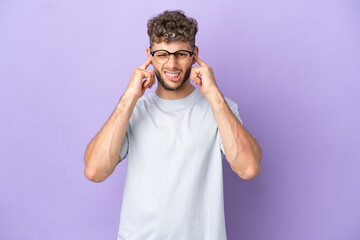 Fototapeta premium Delivery caucasian man isolated on purple background frustrated and covering ears