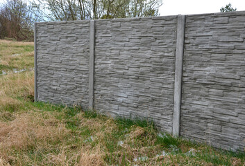 fencing with a gray panel fence in the garden with a lawn and concrete interlocking paving. A panel...