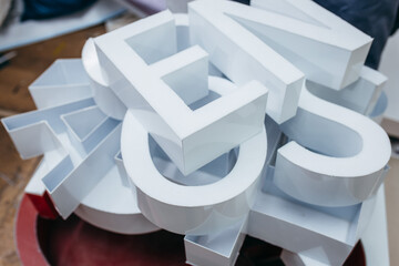 Production of metal white 3d letters on different form. Elements of signboard