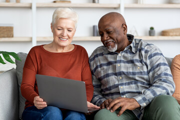 happy senior lady showing her friend photos on laptop